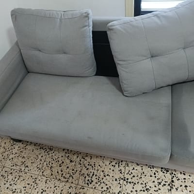 ספה אפורה עם כריות על רצפת אריחים