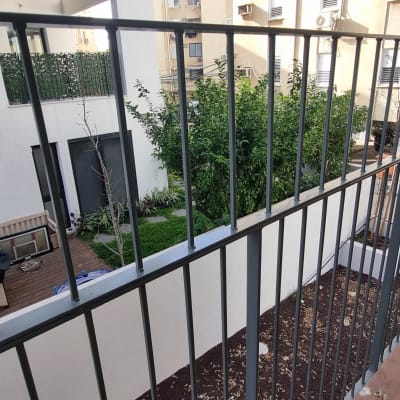 מעקה מתכת במרפסת עם עציץ על המעקה