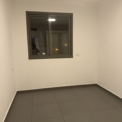 חדר ריק עם חלון ורצפת אריחים אפורה