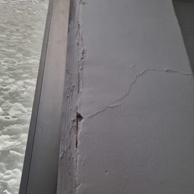 קיר עם סדקים ותיקונים ליד חלון