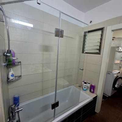 מקלחת עם דלת זכוכית ומוצרי טיפוח על שפת האמבטיה