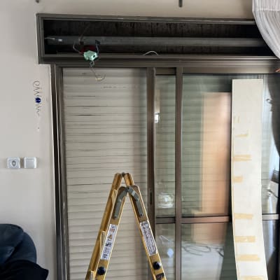 סולם מול חלון עם תריסים בתהליך תיקון