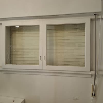 חלון זכוכית עם תריסים סגורים על קיר לבן