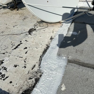 איטום גג עם חומר לבן ליד צלחת לוויין