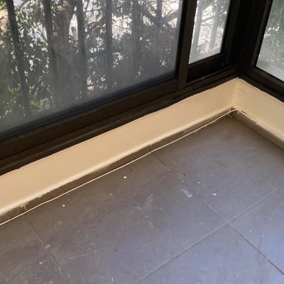 איטום פינה עם חומר איטום לבן ליד חלון זכוכית