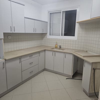 מטבח ריק עם ארונות לבנים ומשטח עבודה