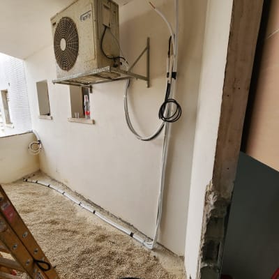 יחידת מיזוג אוויר מותקנת על קיר עם צינורות חשופים