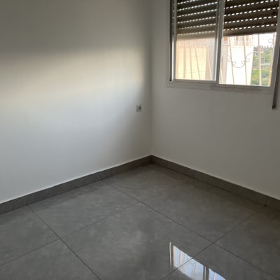 חלון עם תריסים חומים פתוחים למחצה