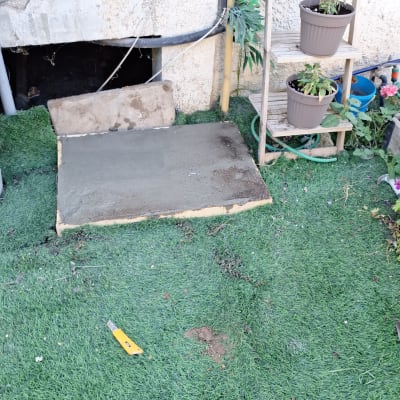 יציקת משטח בטון קטן בחצר לצד דשא סינתטי