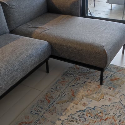 ספה אפורה עם שטיח צבעוני על רצפה לבנה