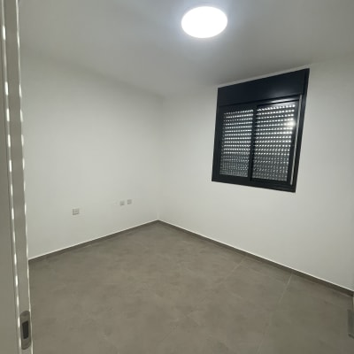 חדר ריק עם קירות צבועים ורצפת אריחים אפורה