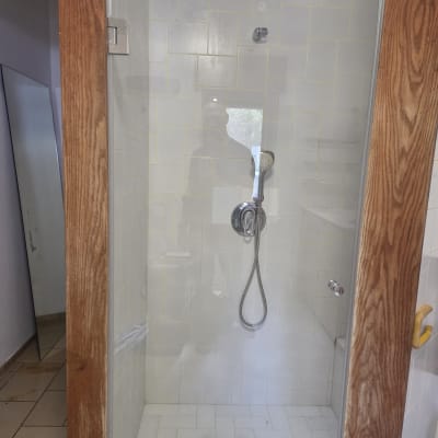 מקלחת עם דלת זכוכית וראש מקלחת