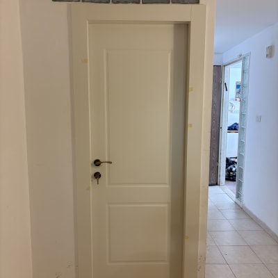 דלת לבנה מותקנת בקיר עם רצפת קרמיקה