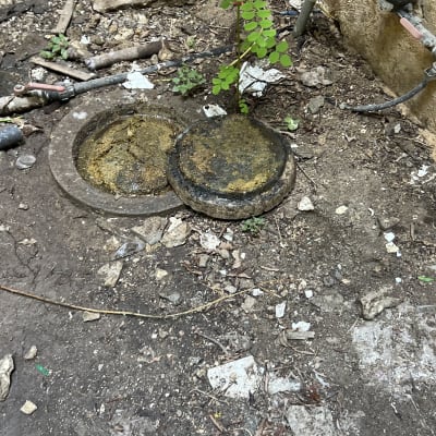 צינור מים וברז ליד מכסה ביוב בחצר