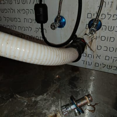 צינורות וחיבורים מתכתיים על רקע קיר עם טקסט בעברית