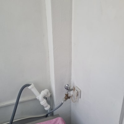 צינור מים מחובר לברז על קיר לבן