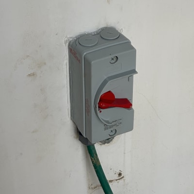 שקע חשמלי אפור עם כבל ירוק מחובר