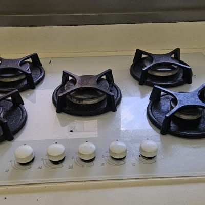 כיריים גז עם חמישה מבערים וכפתורי שליטה לבנים