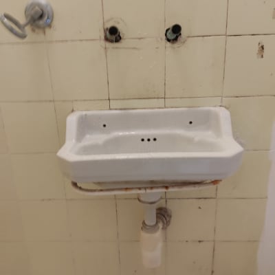 כיור ישן עם צנרת חשופה על קיר
