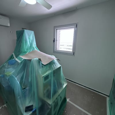 חדר עם רהיטים מכוסים בניילון לקראת צביעה