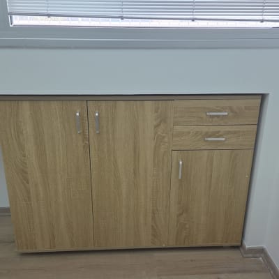 ארון עץ עם דלתות ומגירות מתחת לחלון