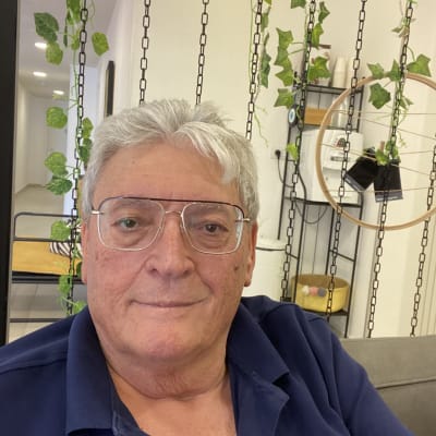 אדם יושב על ספה עם צמחייה תלויה ברקע