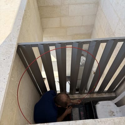 אדם עובד עם ציוד טכני באזור סגור, חוט אדום נראה בתמונה