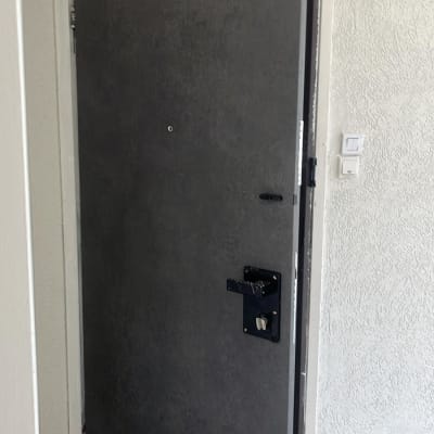 דלת אפורה פתוחה עם ציפוי כהה ומנעול.