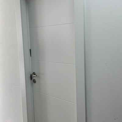 דלת לבנה עם ידית מתכת על קיר לבן