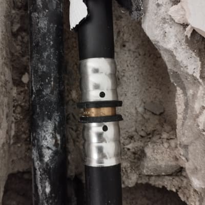 צינור שחור עם מחבר מתכת בקיר בטון