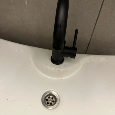 ברז שחור וכיור לבן עם ניקוז מתכת