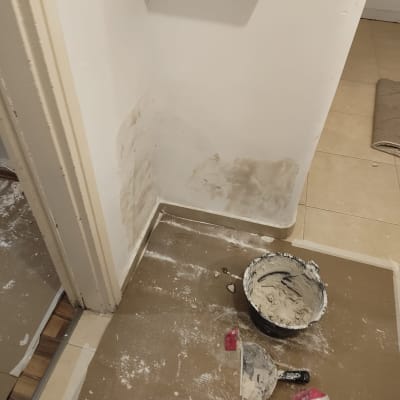 כלי עבודה וחומרי טיח על רצפה ליד קיר