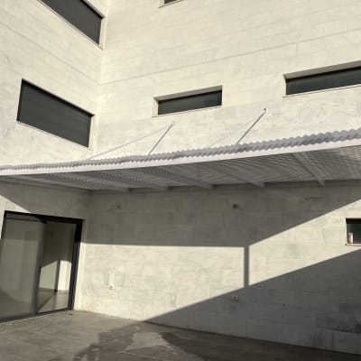 פרגולה מאלומיניום מחוברת לקיר חיצוני של בניין