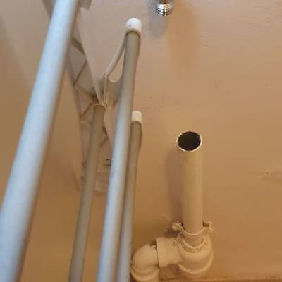 צינור מים לבן עם ברז מתכת על הקיר