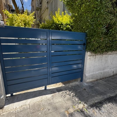 שער מתכת כחול עם צמחייה ברקע