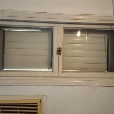 חלון זכוכית עם תריסים ומזגן על הקיר