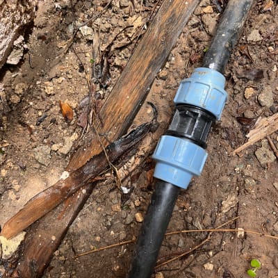 צינור שחור עם מחבר כחול באדמה