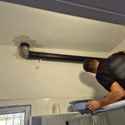אדם עובד על צינור תקרה עם כלים