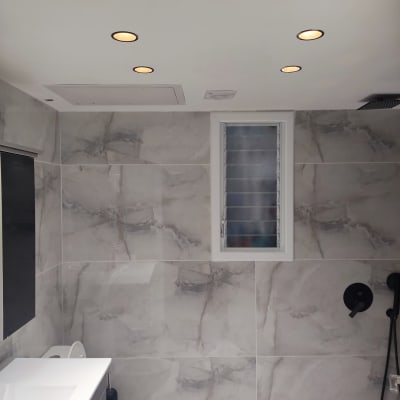 חדר אמבטיה משופץ עם תאורה שקועה וקירות שיש