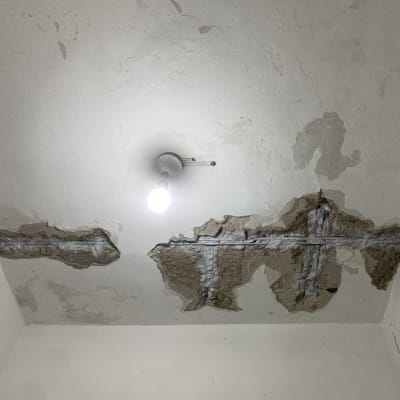 תקרה מתקלפת עם טיח חשוף ונורה תלויה