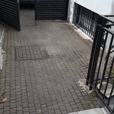 שער שחור פתוח בחניה עם ריצוף אבן