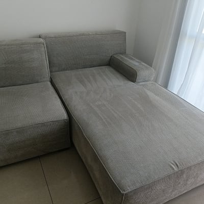 ספה אפורה ליד חלון עם וילון לבן