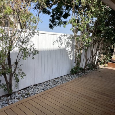 דק עץ עם גדר לבנה ועצים מסביב