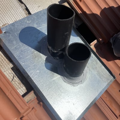 צינורות שחורים על גג רעפים עם לוח מתכת