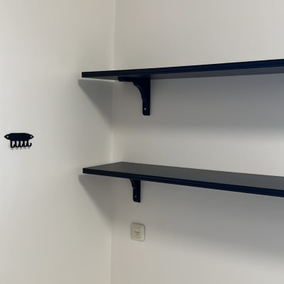 שתי מדפים שחורים מותקנים על קיר לבן