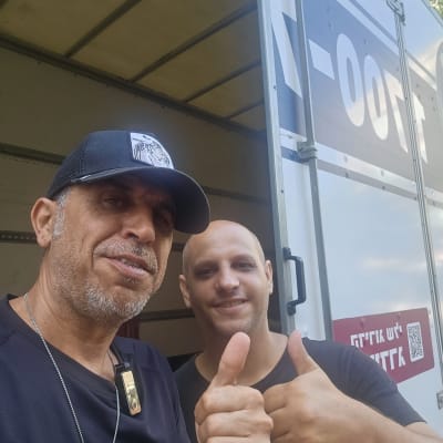 שני אנשים ליד משאית הובלה עם אגודלים למעלה