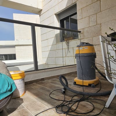 מכונת ניקוי ומיכל על מרפסת עם רצפת עץ