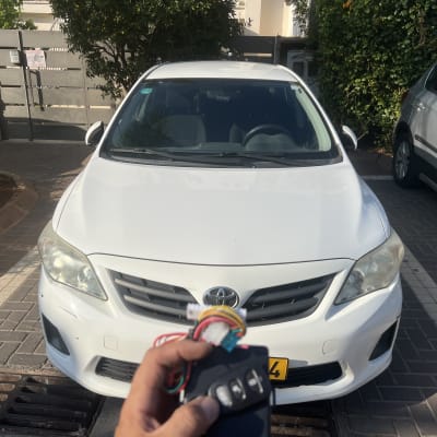 מנעולן רכב מחזיק שלט מול רכב לבן