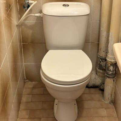 אסלה עם צינורות מים וקיר אריחים