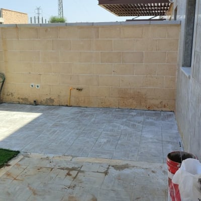 ריצוף חדש בחצר עם קיר בלוקים וגדר מתכת